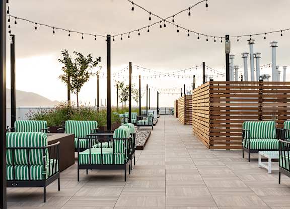 A patio with green striped chairs and wooden tables.