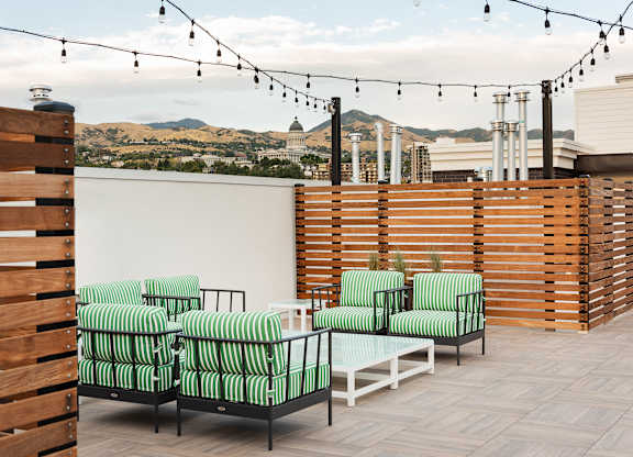 A patio with green striped chairs and a view of the city.