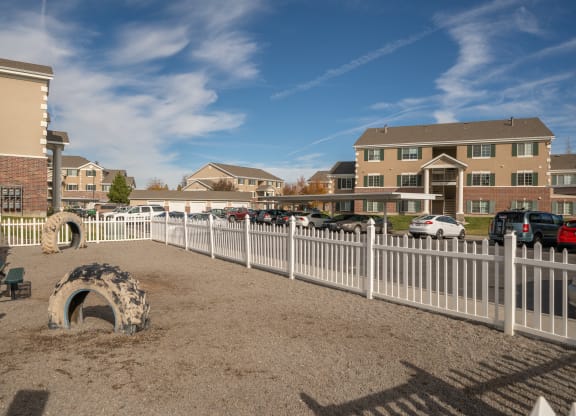a fenced in dog park in front of a building