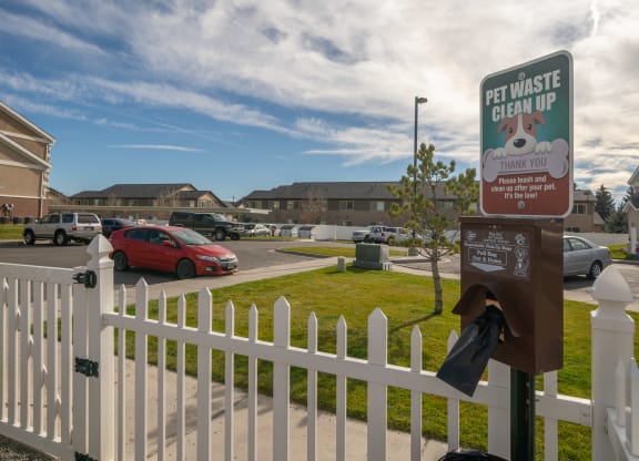 a white picket fence with a sign that says pet waste clean up