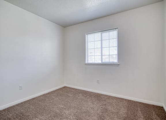a bedroom with white walls and a window