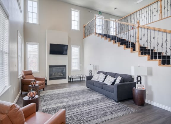 a living room with a staircase in the background and a couch and chair in the foreground