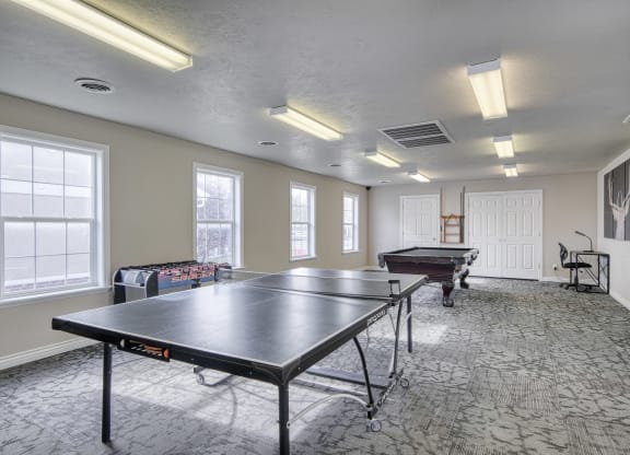 a recreation room with two ping pong tables and a foosball table