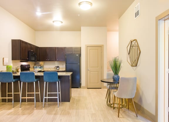 a kitchen with a bar and stools next to a living room with a refrigerator at Sugar House Apartments By Urbana, Salt Lake City, UT, 84105