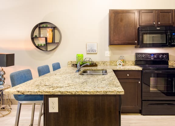 a kitchen with a granite counter top and black appliances at Sugar House Apartments By Urbana, Salt Lake City, UT, 84105