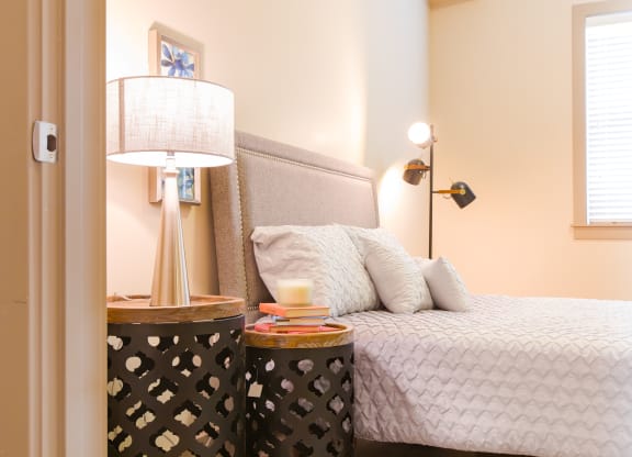a bedroom with a bed and a nightstand with a lamp at Sugar House Apartments By Urbana, Salt Lake City, UT, 84105