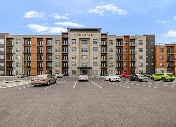 A parking lot in front of a multi-story apartment building named Reverie.