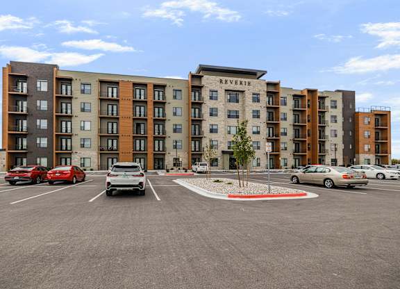 A parking lot in front of a multi-story apartment building.