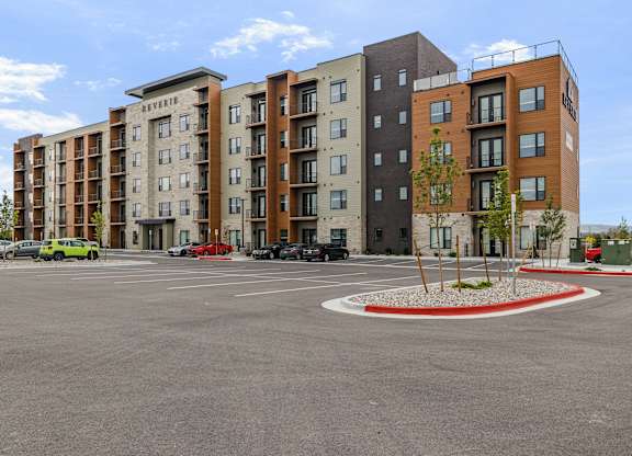 A parking lot in front of a multi-story apartment building.