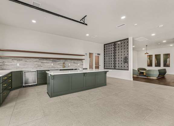 A modern kitchen with dark green cabinets and a stone backsplash.