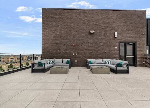 A modern patio area with a brick wall and two couches.