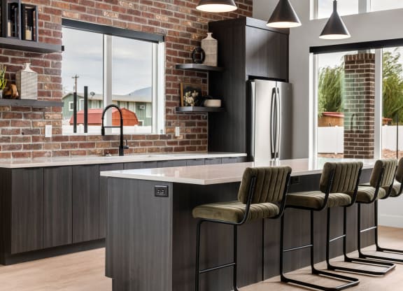 a kitchen with a brick wall and a large island with bar stools