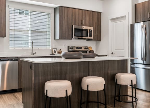 a kitchen with a large island with three stools in front of it