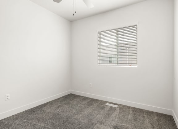 a bedroom with white walls and a window