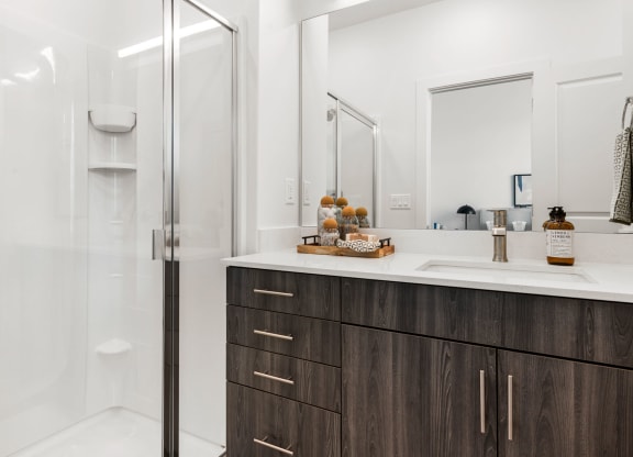 a bathroom with white walls and a wooden vanity with a white countertop