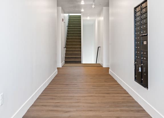 a long hallway with white walls and wood floors and a staircase