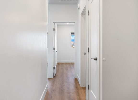 an empty hallway with white walls and wood floors