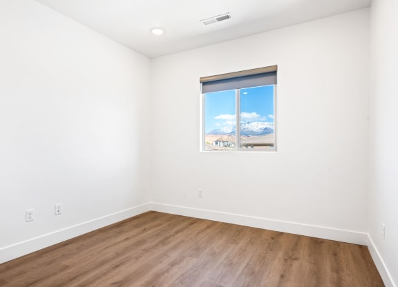 a room with white walls and wood floors and a window