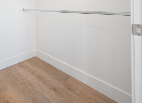 a room with white walls and a wooden floor and a white closet