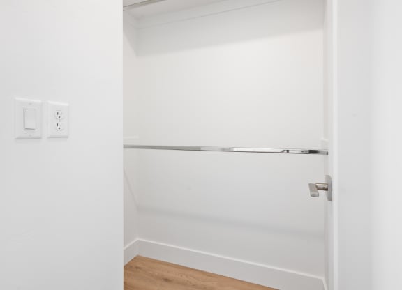 an empty closet in a white room with a door open