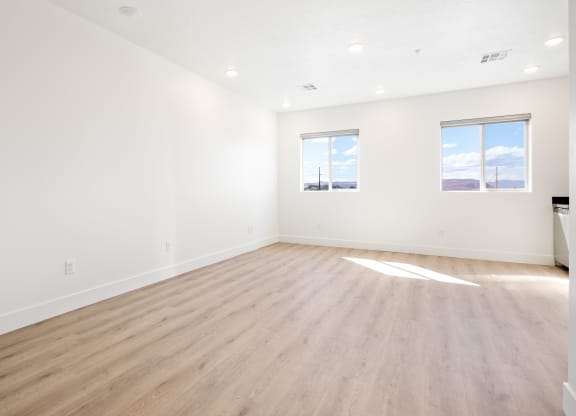 an empty living room with wood floors and white walls