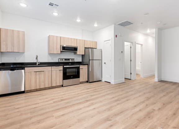 an empty kitchen with wood flooring and stainless steel appliances