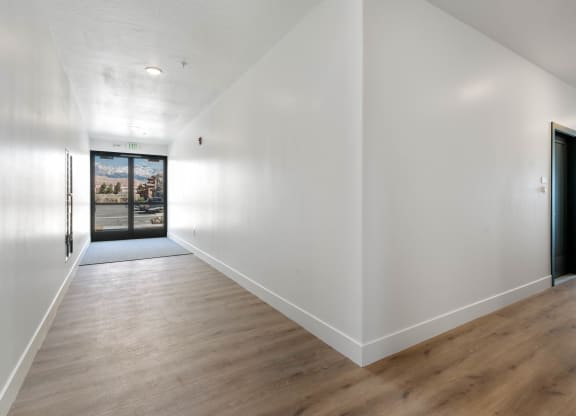 a hallway with white walls and wood floors and a black door