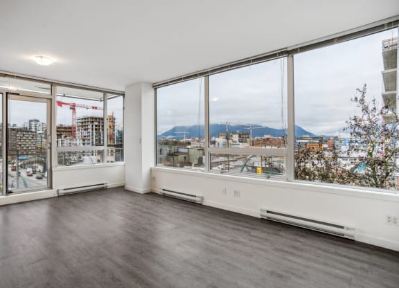 an empty living room with large windows and a city view