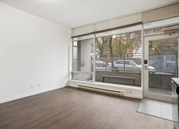 an empty living room with a large window and wood flooring