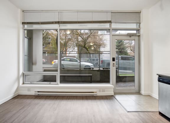 an empty living room with a large window and a car outside
