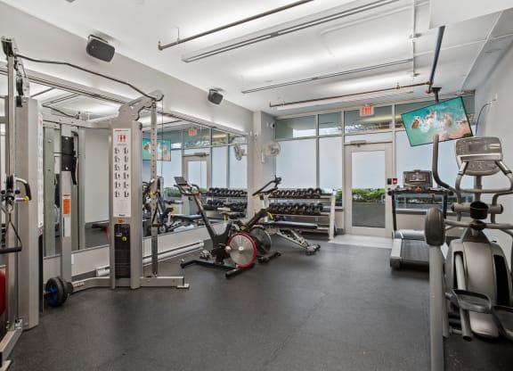 a gym with weights and cardio equipment on the floor and windows