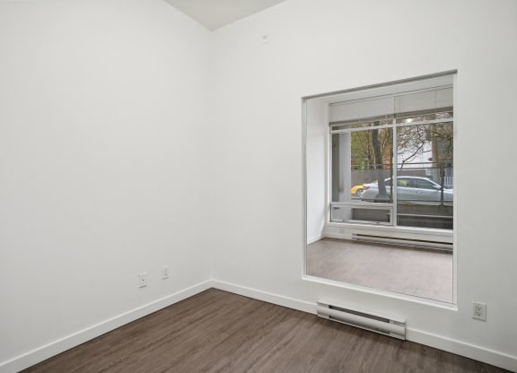 a living room with a large window and wood flooring