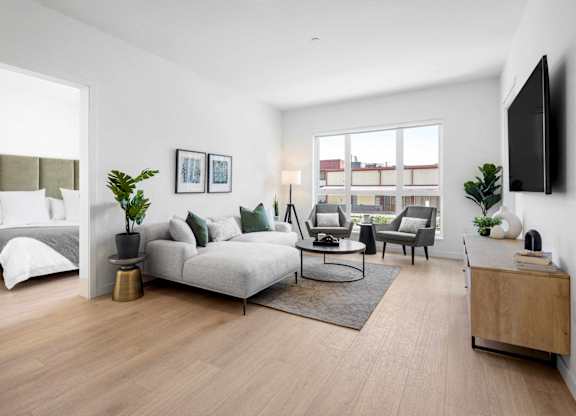 A modern living room with a grey sofa, a coffee table, and a television on the wall.