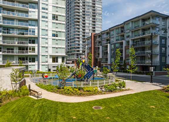 A playground with a blue slide is surrounded by apartment buildings.