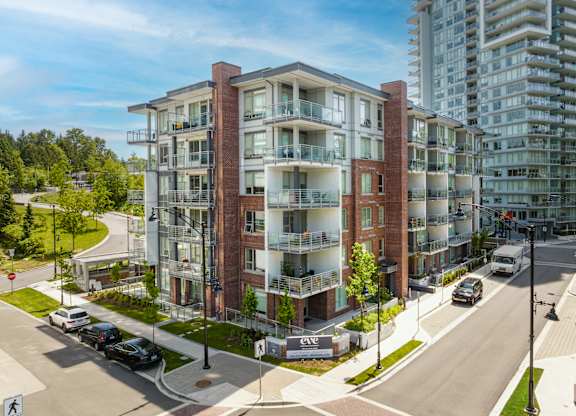 A modern apartment building with a parking lot in front.