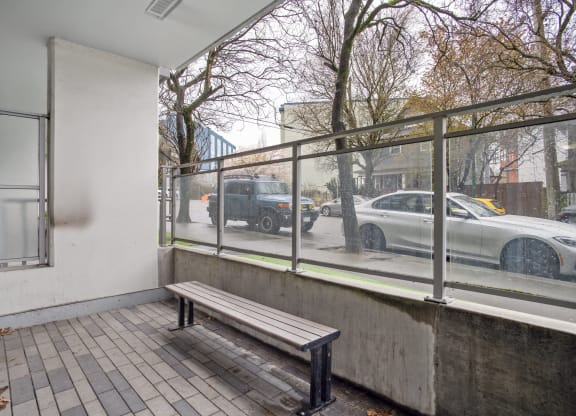 a bench on a sidewalk next to a building with a window