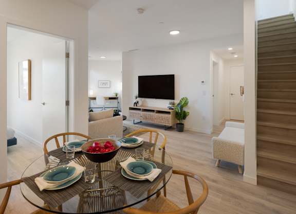 A modern dining room with a glass table set for four.