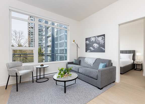A grey couch with a white throw is in the living room.