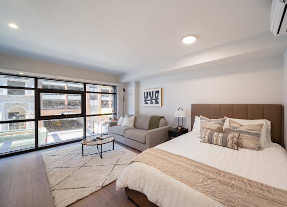 A bedroom with a large bed and a view of the street outside.