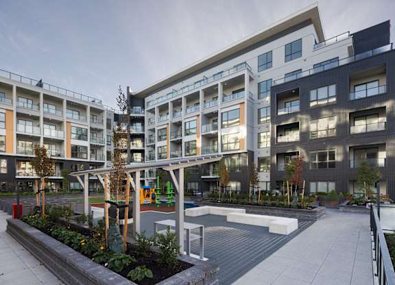 A modern apartment complex with a playground in the courtyard.