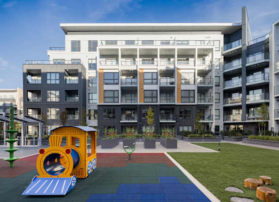 A playground with a train slide in front of a large building.