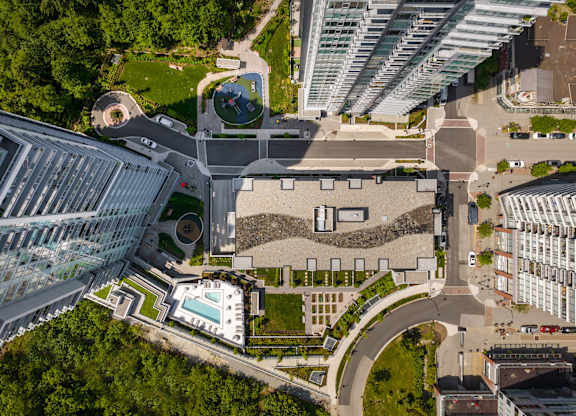 A modern building with a glass facade and a circular courtyard with a fountain.