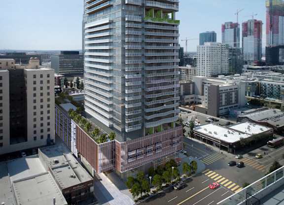 A tall, modern building with a glass facade stands in the middle of a cityscape.