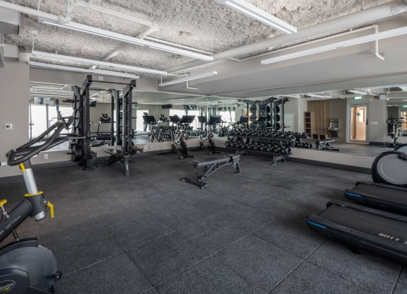 a gym with treadmills and other exercise equipment in a building with cement floors
