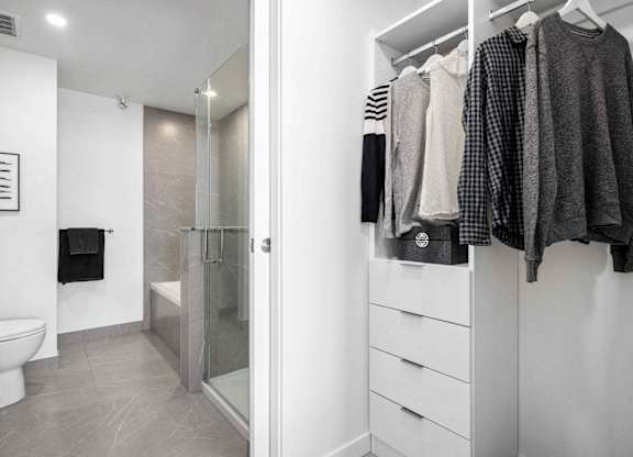 A white bathroom with a walk in shower and a towel hanging on the wall.