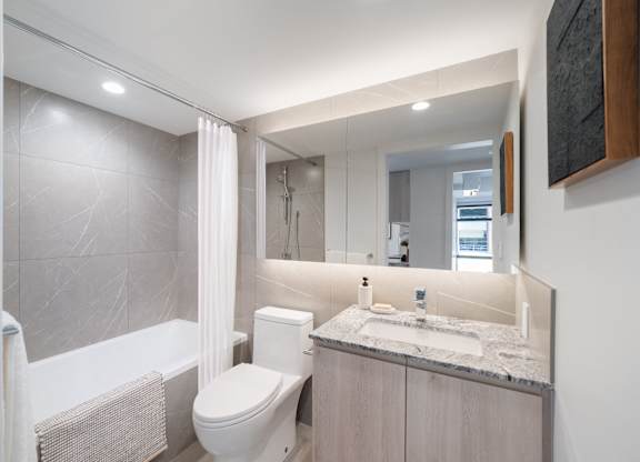 A modern bathroom with a white toilet, sink, and bathtub.