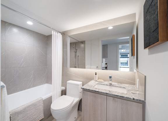 A modern bathroom with a white toilet, sink, and bathtub.