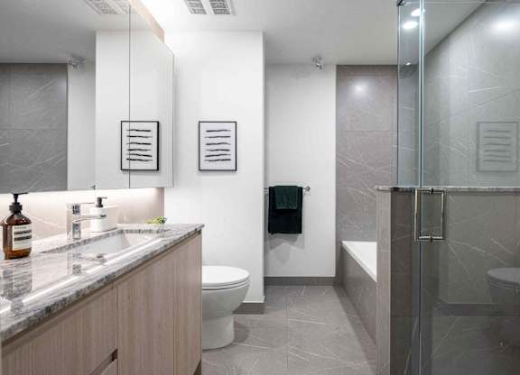 A bathroom with a toilet, sink, and mirror.