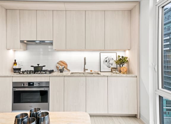 a kitchen with white cabinets and a table and a window