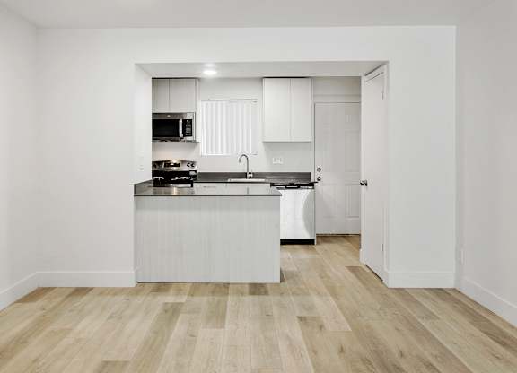 A kitchen with white cabinets and a wooden floor.